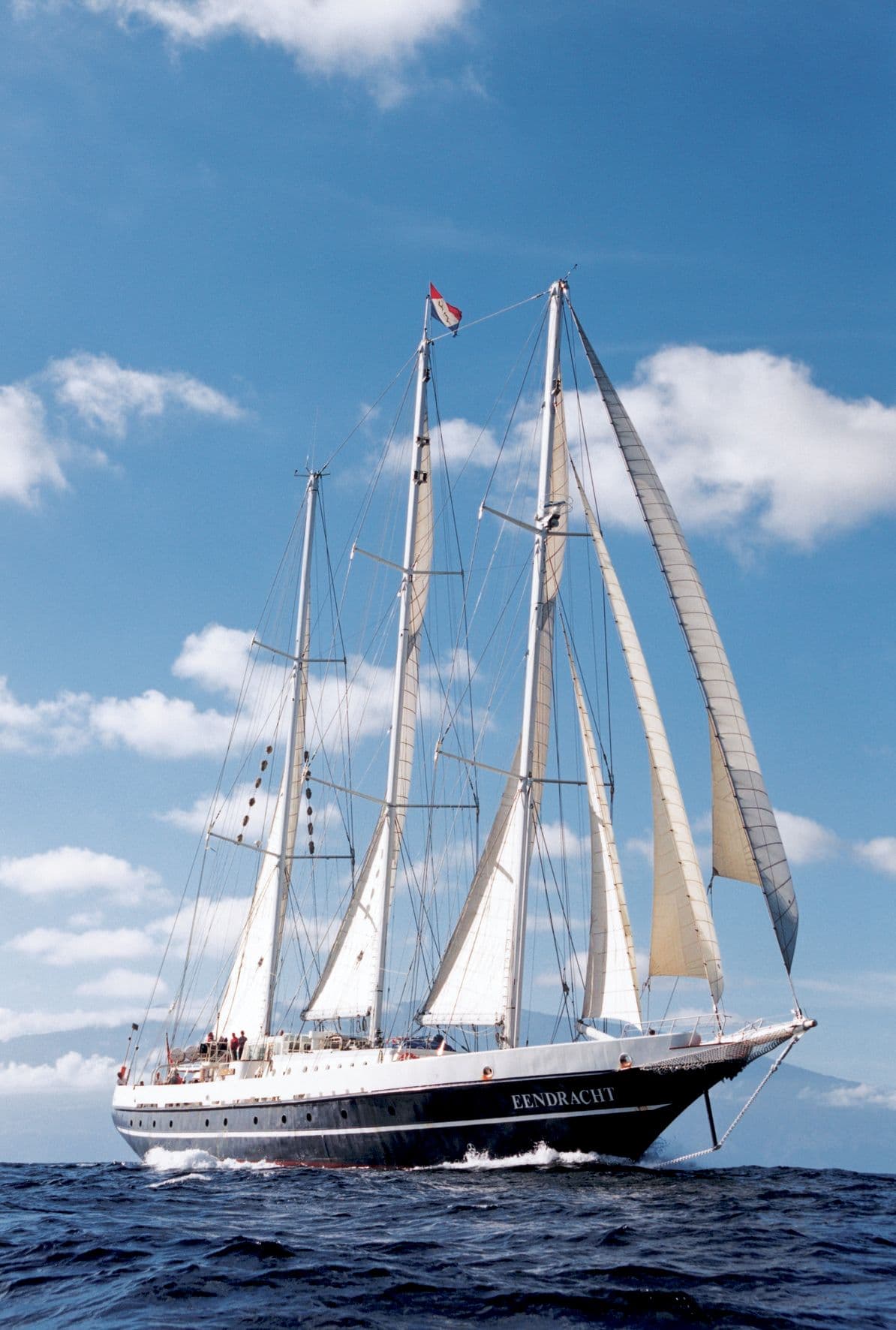De zeilen van de Eendracht tegen een blauwe lucht met wolken