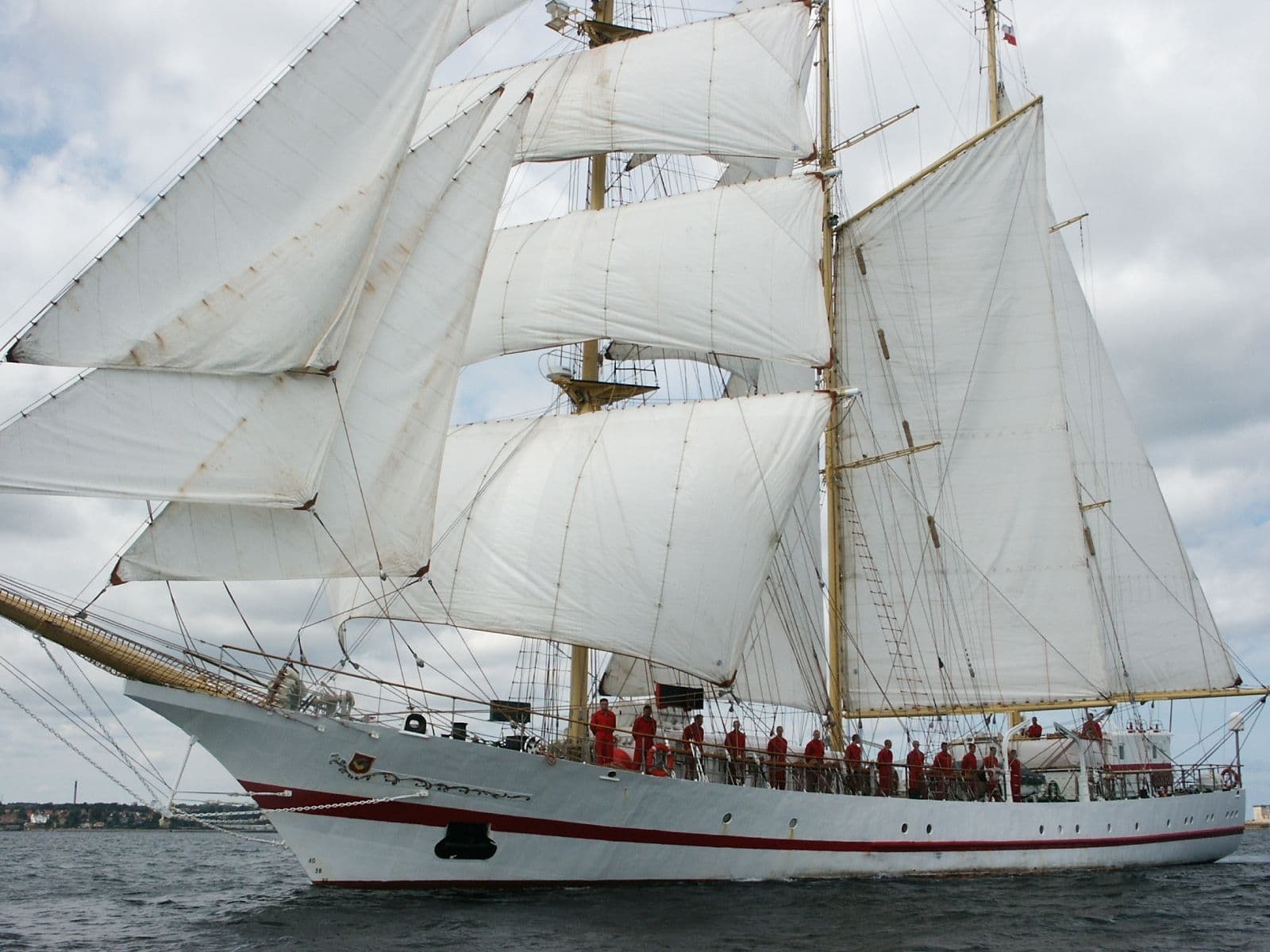 Bemanning van Tall Ship de Iskra staan in hun rode kleding aan de zijkant van het schip