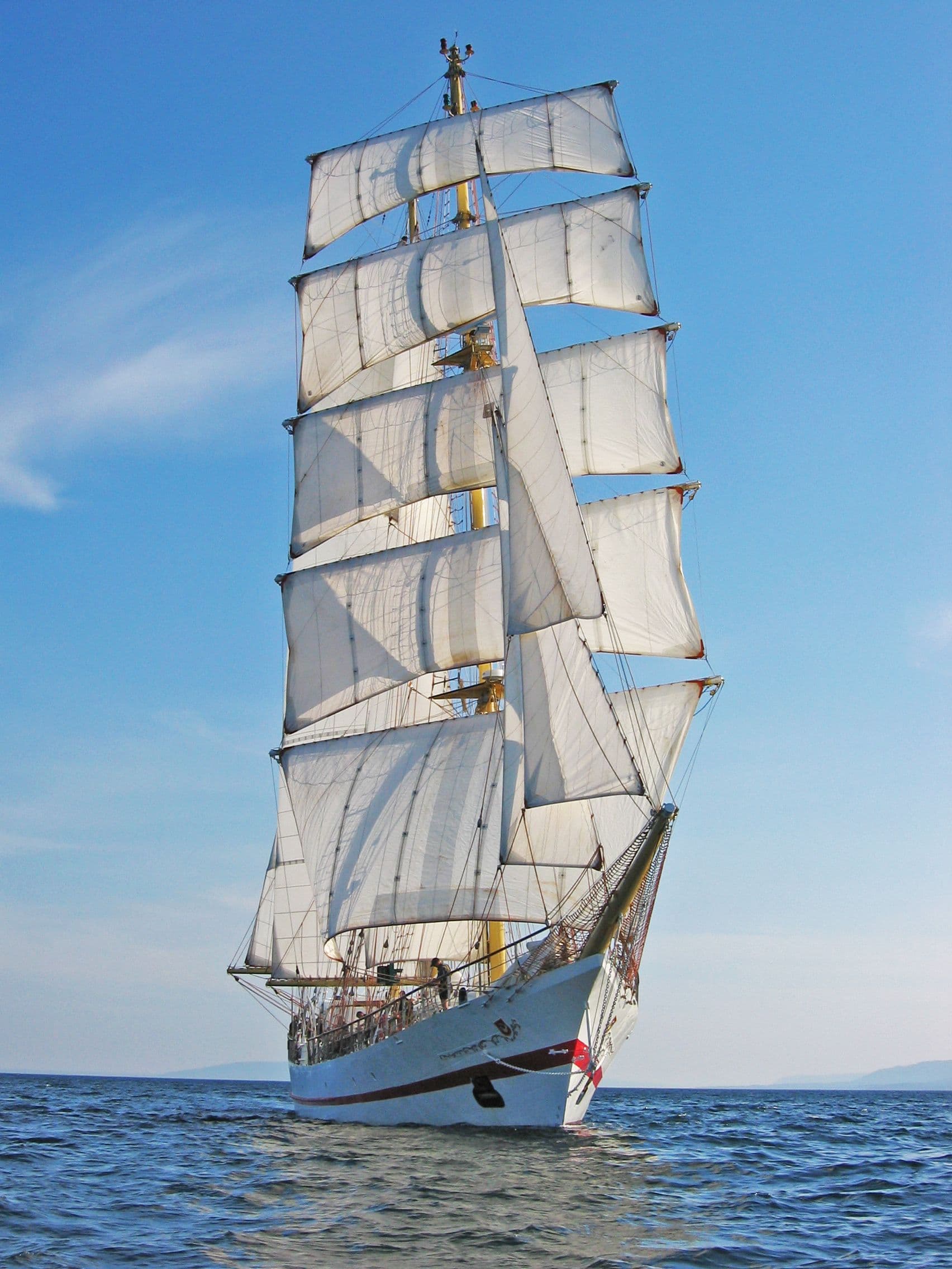 De zeilen van de Iskra staan in de zon tegen een strak blauwe lucht