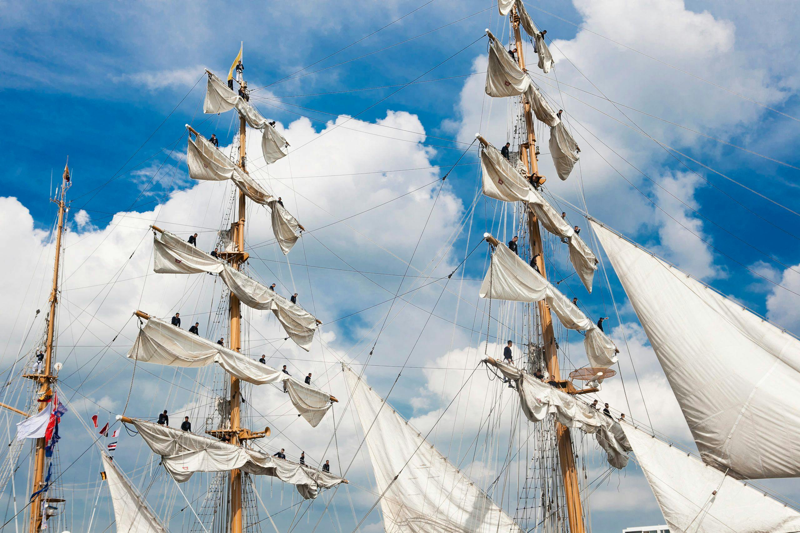 Bemanningsleden van de Guayas staan de de masten van het schip