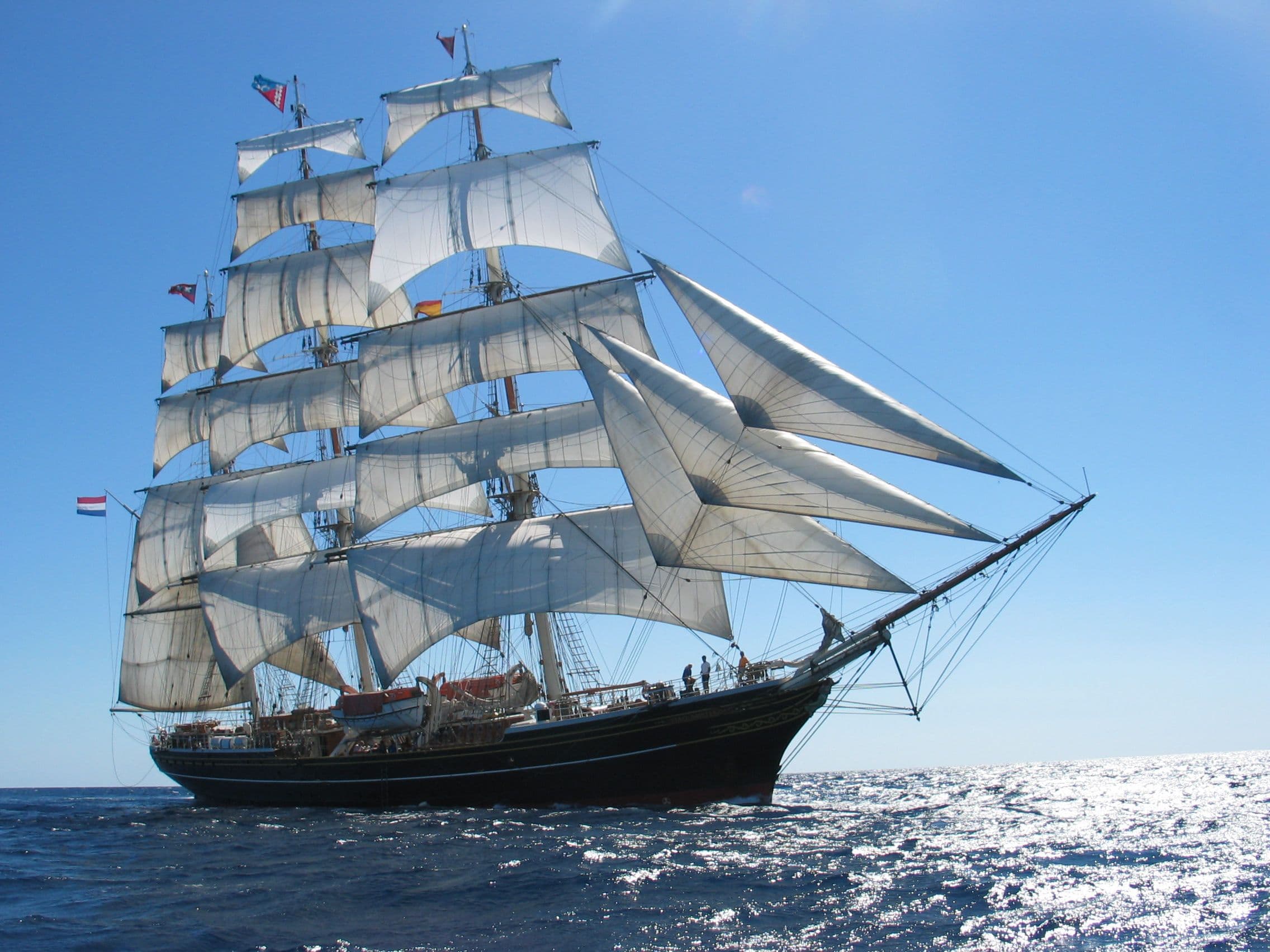 Clipper Stad Amsterdam ligt schuin in het zee bij een strak blauwe lucht