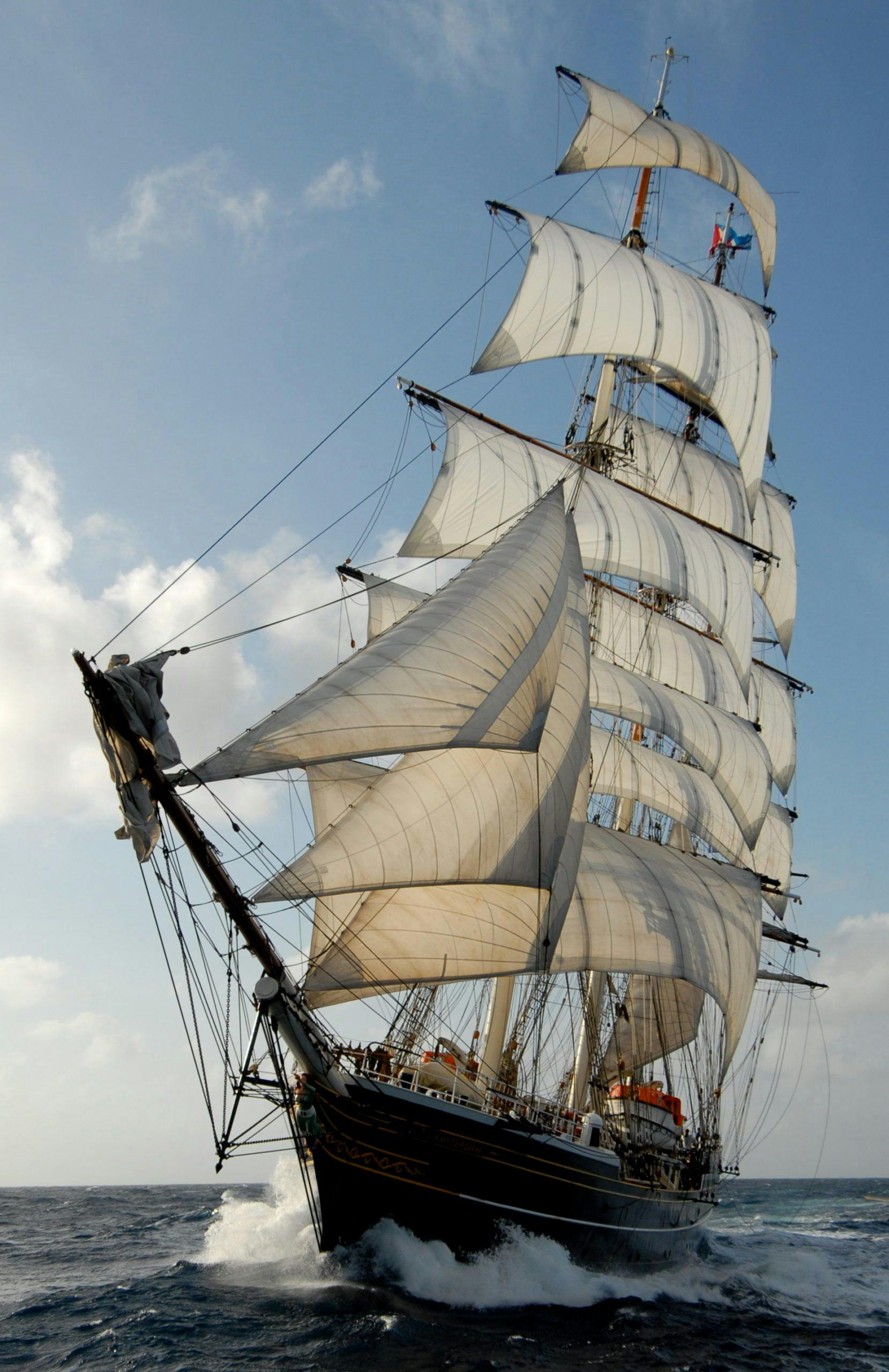 De clipper Stad Amsterdam vaart door de zee terwijl de golven tegen de boot slaan